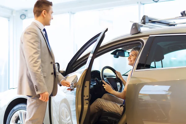 Mulher feliz com negociante de carro em auto show ou salão de beleza — Fotografia de Stock