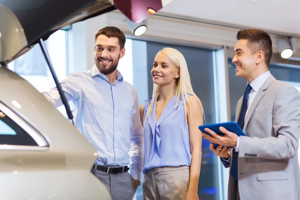 Glückliches Paar mit Autohändler in Auto-Show oder Salon — Stockfoto