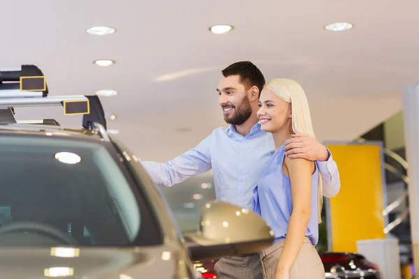 happy couple buying car in auto show or salon