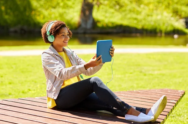 Mujer africana feliz con la PC tableta y auriculares — Foto de Stock