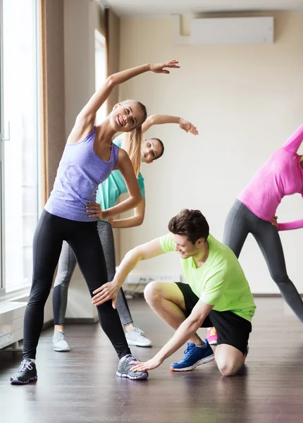 Grupp av leende människor stretching i gym — Stockfoto