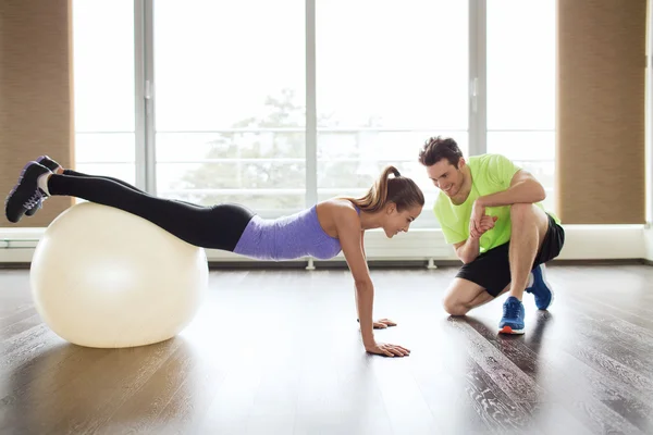 Sorridente homem e mulher com bola de exercício no ginásio — Fotografia de Stock