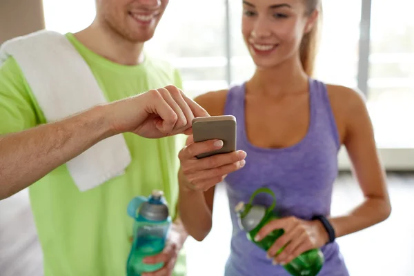 Mujer feliz y entrenador mostrando teléfono inteligente en el gimnasio — Foto de Stock