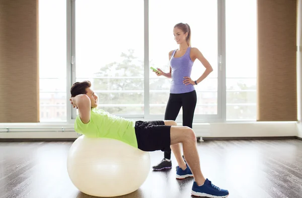 Glimlachende man en vrouw met oefening bal in gym — Stockfoto