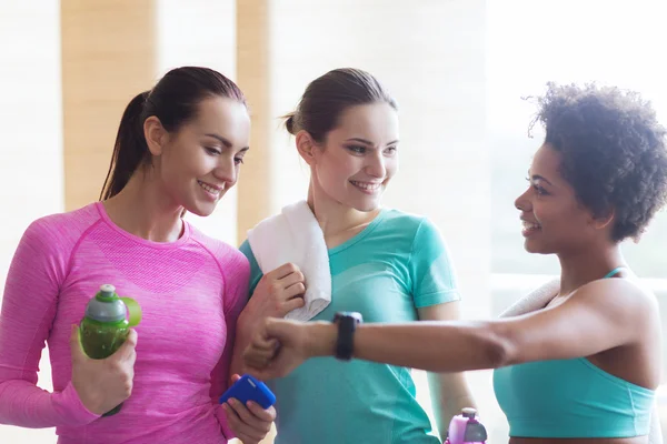 Mujeres felices mostrando tiempo en reloj de pulsera en el gimnasio — Foto de Stock