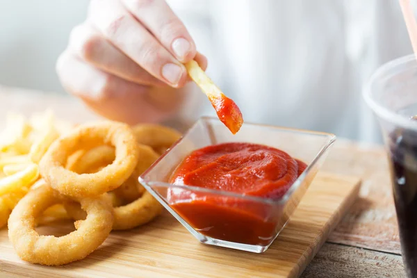 Close up van hand Franse frietjes dompelen in ketchup — Stockfoto