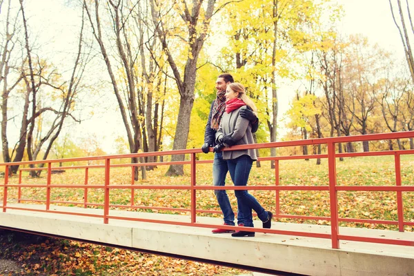 Lachende paar knuffelen op brug in herfst park — Stockfoto