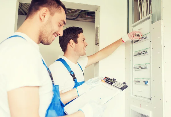 Builders with clipboard and electrical panel — Stock Photo, Image