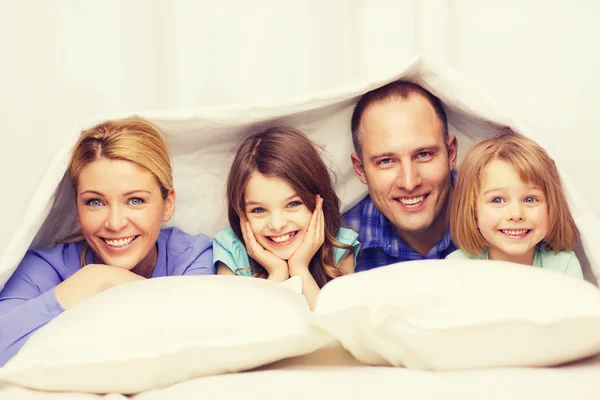 Familia feliz con dos niños bajo manta en casa — Foto de Stock