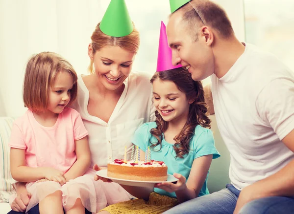 Familia sonriente con dos niños en sombreros con pastel —  Fotos de Stock