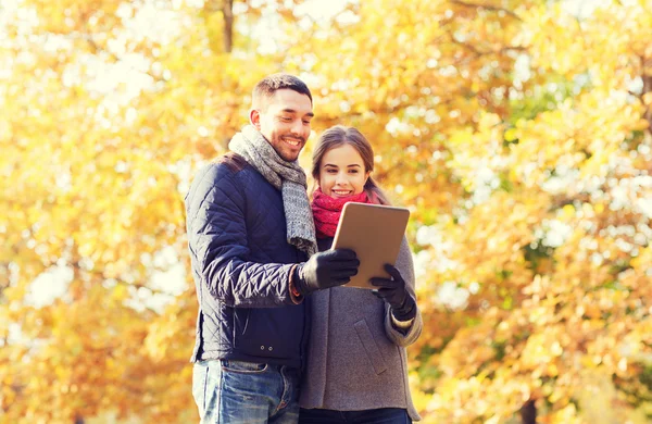 Sonriente pareja con tableta PC en el parque de otoño — Foto de Stock