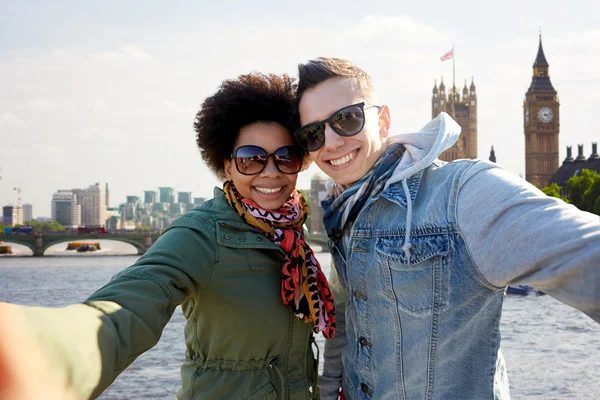 Happy teenage couple taking selfie in london city — Stock Photo, Image