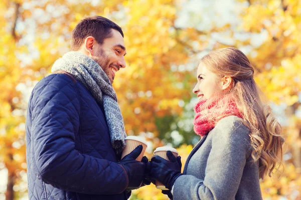 Χαμογελώντας ζευγάρι με φλιτζάνια καφέ στο πάρκο φθινόπωρο — Φωτογραφία Αρχείου