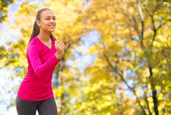 Smiling woman running outdoors at autumn — Stok fotoğraf