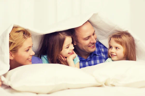 Szczęśliwa rodzina z dwójką dzieci pod kocem w domu — Zdjęcie stockowe