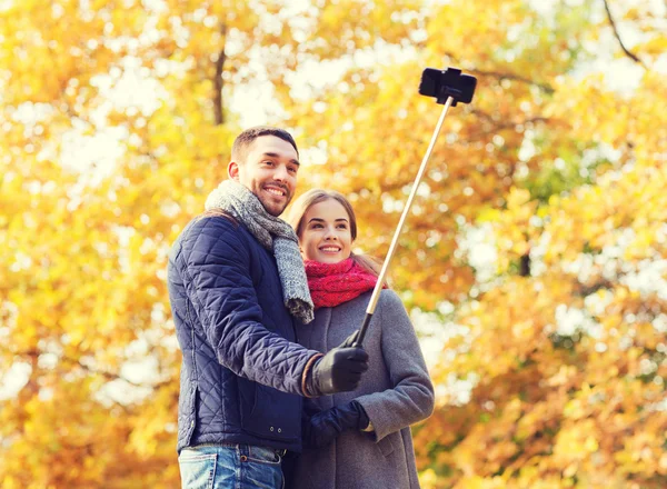 Lachende paar met smartphone in herfst park — Stockfoto