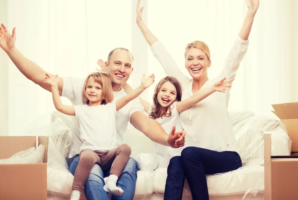 Lächelnde Eltern und zwei kleine Mädchen im neuen Zuhause — Stockfoto