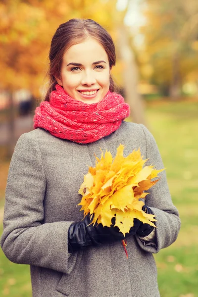 Mulher sorridente com cacho de folhas no parque de outono — Fotografia de Stock