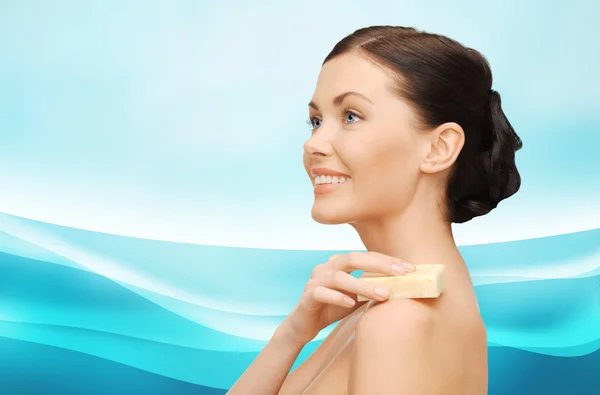 Woman with soap bar over blue wavy background — Stockfoto