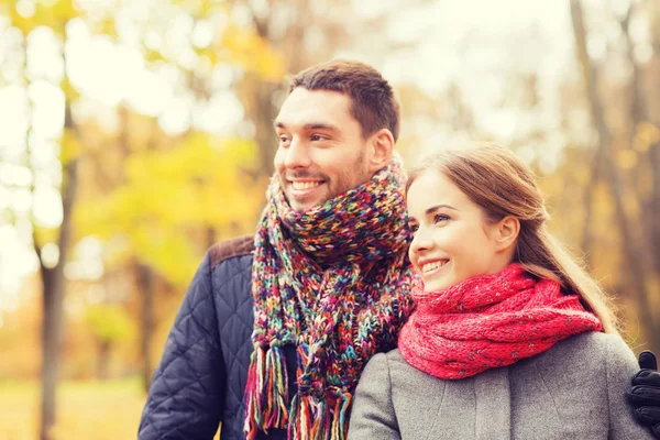 Coppia sorridente che si abbraccia sul ponte nel parco autunnale — Foto Stock