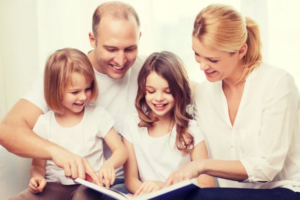 Lachende familie en twee kleine meisjes met boek — Stockfoto