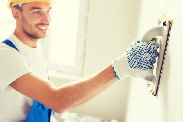 Construtor sorrindo com ferramenta de moagem dentro de casa — Fotografia de Stock