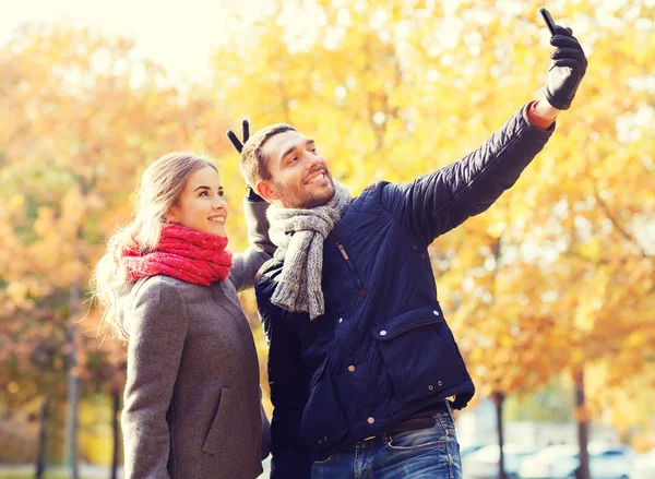 Casal sorridente com smartphone no parque de outono — Fotografia de Stock