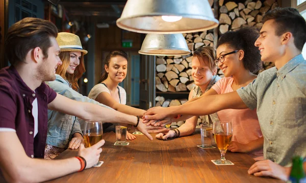 Glückliche Freunde mit Drinks und Händen an der Bar — Stockfoto