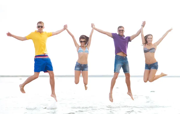 Groep gelukkige vrienden springen op strand — Stockfoto