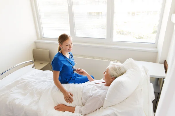 Medico o infermiere in visita a una donna anziana in ospedale — Foto Stock