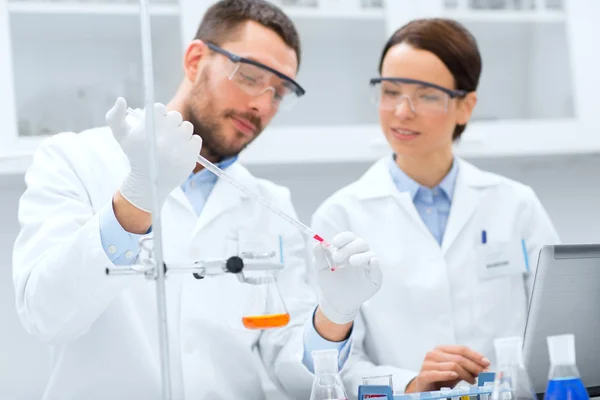 Jóvenes científicos haciendo pruebas o investigaciones en laboratorio — Foto de Stock