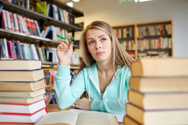 Uttråkad student eller ung kvinna med böcker i biblioteket — Stockfoto