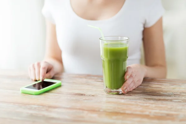 Närbild på kvinna med smartphone och grön juice — Stockfoto