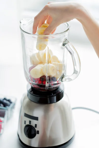 Close up of woman hand adding fruits to blender — Stockfoto