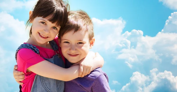 Two happy kids hugging over blue sky and clouds — Zdjęcie stockowe