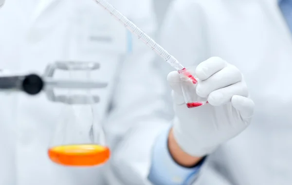 Primer plano de los científicos que llenan el tubo de ensayo en laboratorio — Foto de Stock