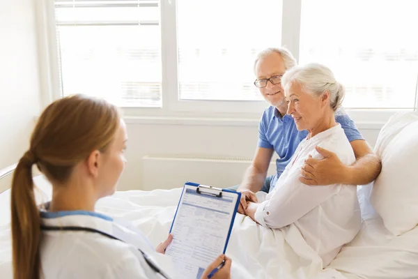 Senior woman and doctor with clipboard at hospital — Stock Photo, Image