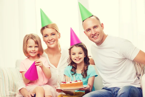 Lachende gezin met twee kinderen in hoeden met cake Stockfoto