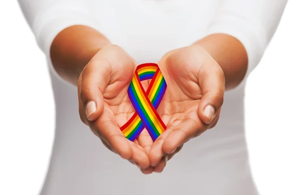 Händer som håller regnbåge gay pride awareness ribbon — Stockfoto