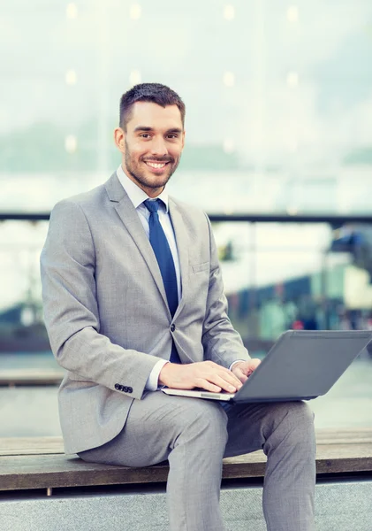 Homem de negócios sorrindo trabalhando com laptop ao ar livre — Fotografia de Stock