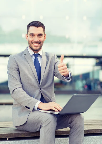 Homem de negócios sorrindo trabalhando com laptop ao ar livre — Fotografia de Stock