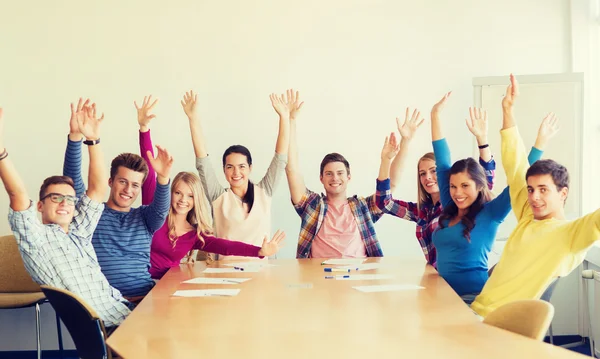 Group of smiling students raising hands in office — Stock Photo, Image