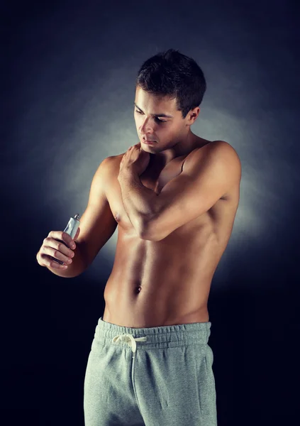 Ung mandlig bodybuilder anvender smertelindring gel - Stock-foto