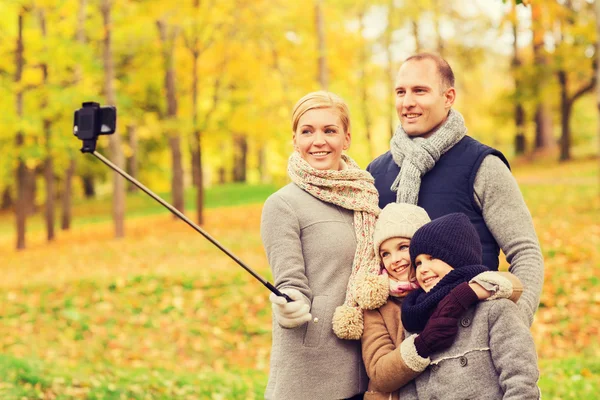 Família feliz com smartphone e monopod no parque — Fotografia de Stock