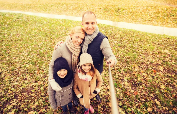 Famiglia felice con bastone selfie nel parco autunnale — Foto Stock