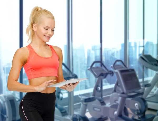 Lächelnde sportliche Frau mit Tablet-PC im Fitnessstudio — Stockfoto