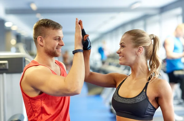 Glimlachende man en vrouw doen hoge vijf in de sportschool — Stockfoto