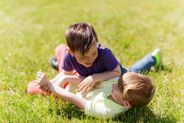 Meninos felizes lutando por diversão na grama — Fotografia de Stock