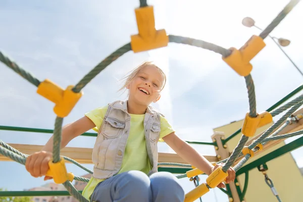 Fröhliches kleines Mädchen klettert auf Kinderspielplatz — Stockfoto