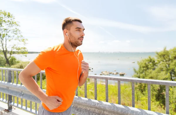 Hombre feliz con auriculares corriendo al aire libre —  Fotos de Stock